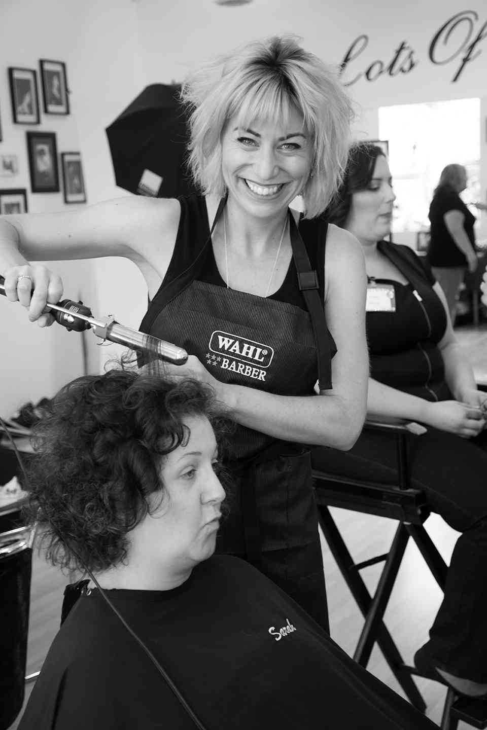 black and white image of woman curling another womans hair at a salon